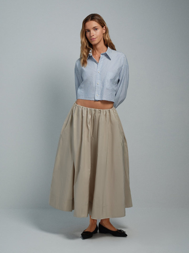 Front on-model view of beige taffeta midi skirt with gathered waist and pockets.