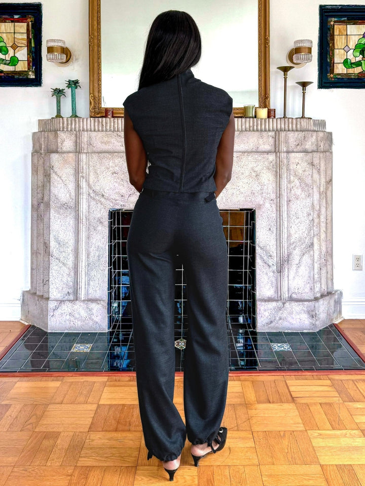 Back view of a model wearing a fitted black sleeveless top paired with black relaxed-fit pants that have drawstring-adjustable ankle cuffs.