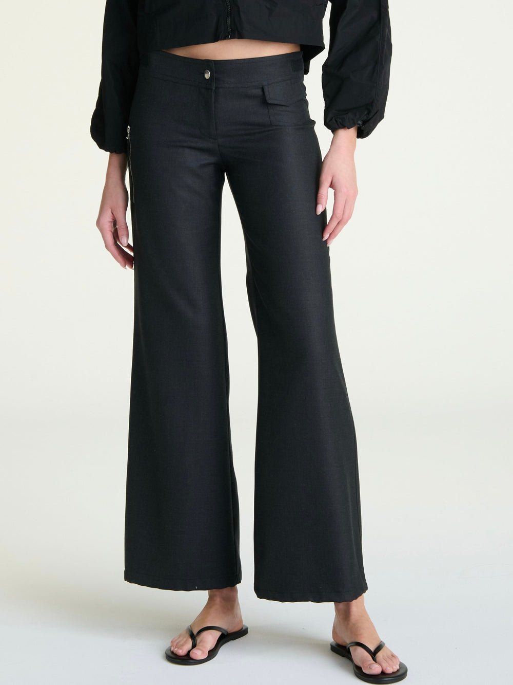 A pair of heather black, lightweight ankle-tie trousers with a zipper pocket and a slight flare at the hem.