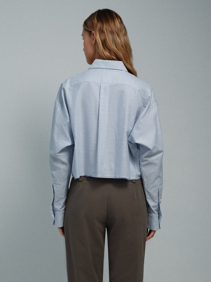 Women’s blue stripe raw-edge oxford shirt, back view showing raw hem and long sleeves.