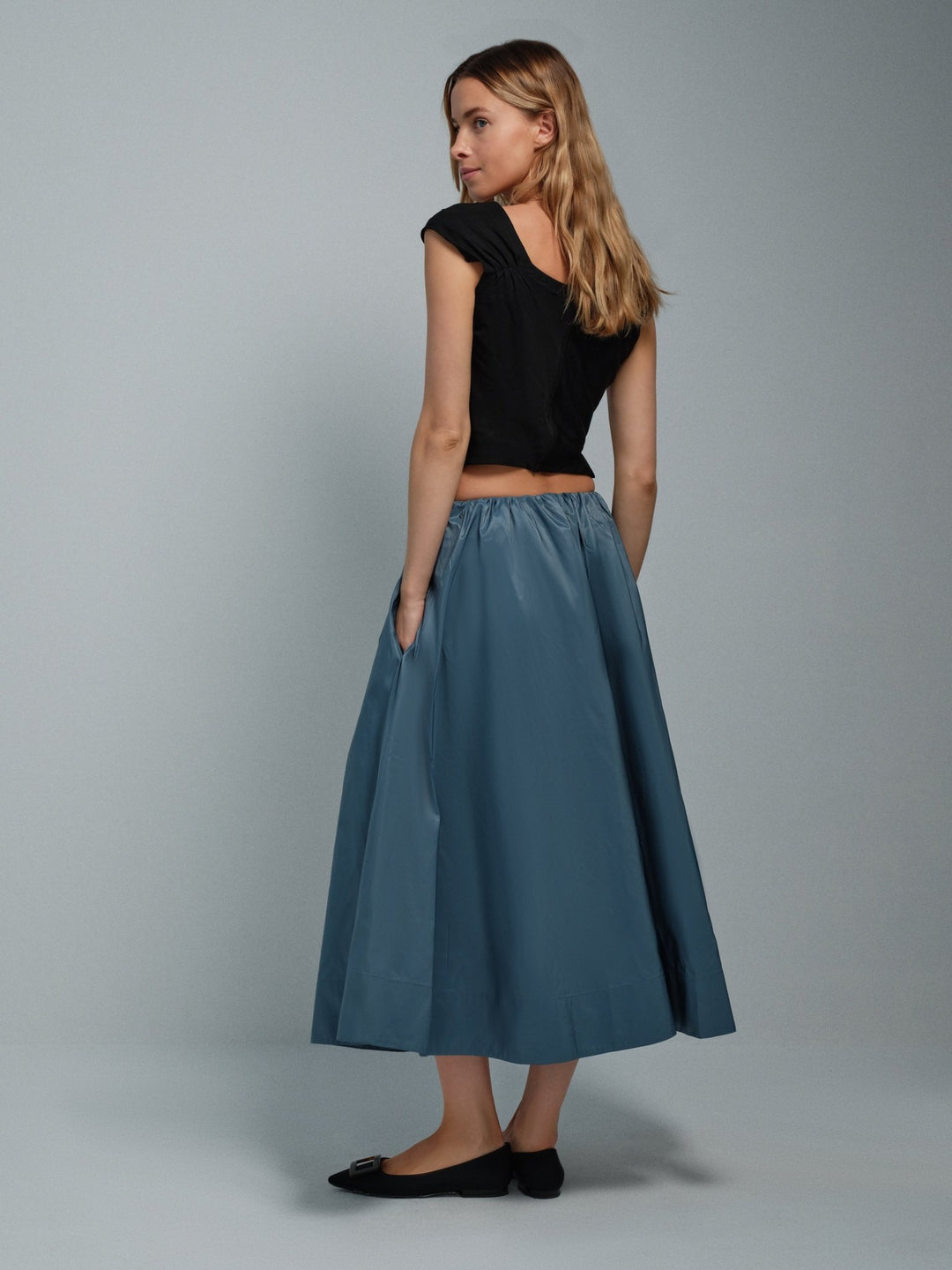 Three-quarter back on-model view of blue taffeta midi skirt with gathered waist.
