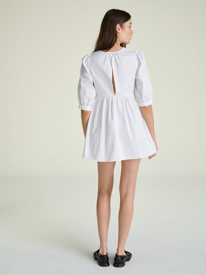 model in a white dress with puff elbow-length sleeves and a baby doll waistline