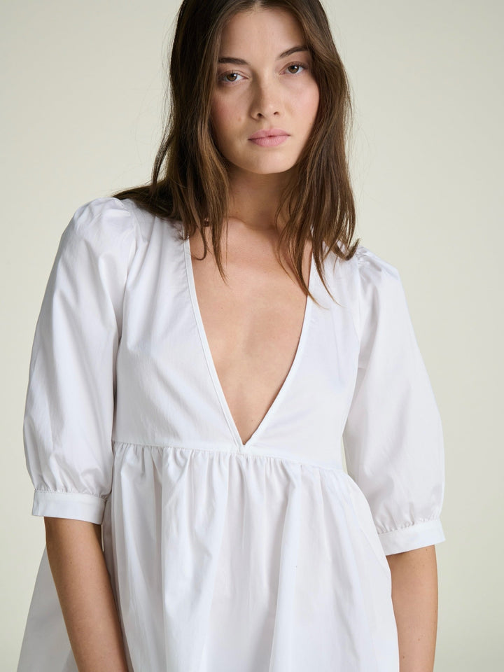 model wearing deep v neck dress with puff sleeves and wide cuffs