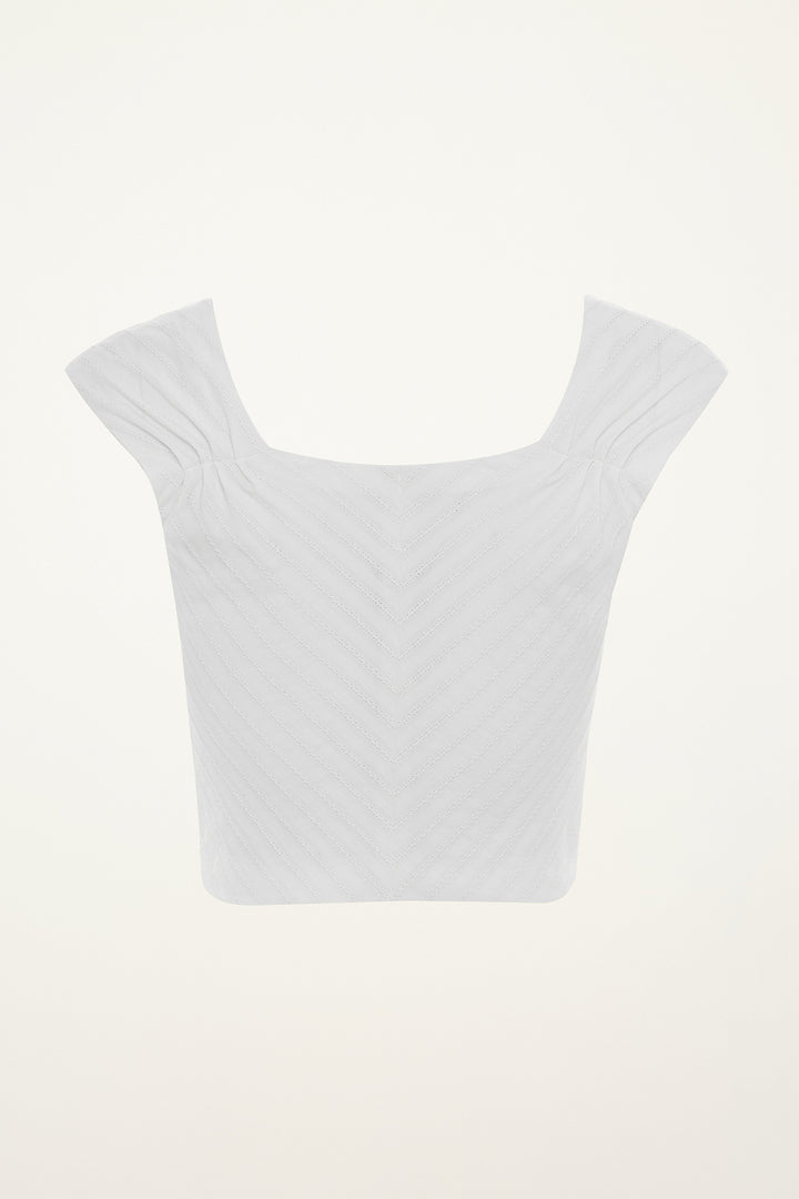 White crop top on a mannequin against a grey background