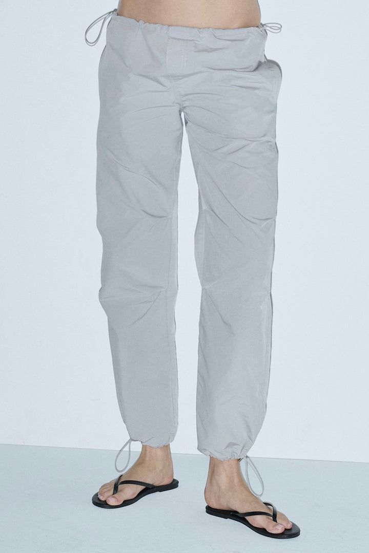 soft grey parachute pants with drawstrings at the waist and at the ankles 