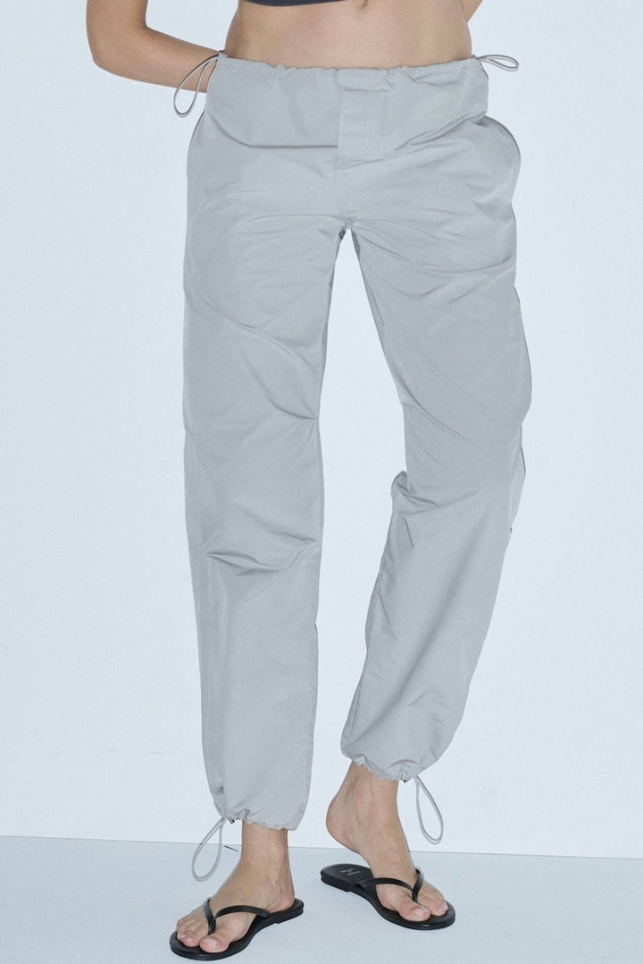 A pair of space grey luxury parachute pants with drawstrings and a relaxed fit.