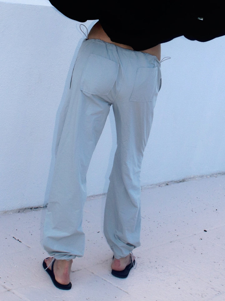 Model from the back wearing light grey drawstring pants with visible back pockets and a loose black top.