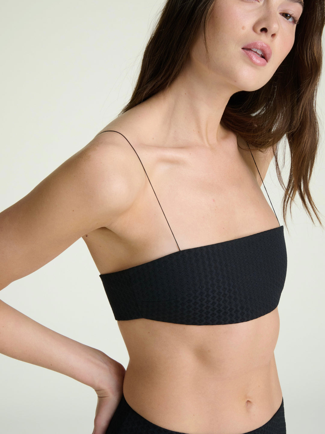model wearing a black bandeau with micro elastic straps on a grey background