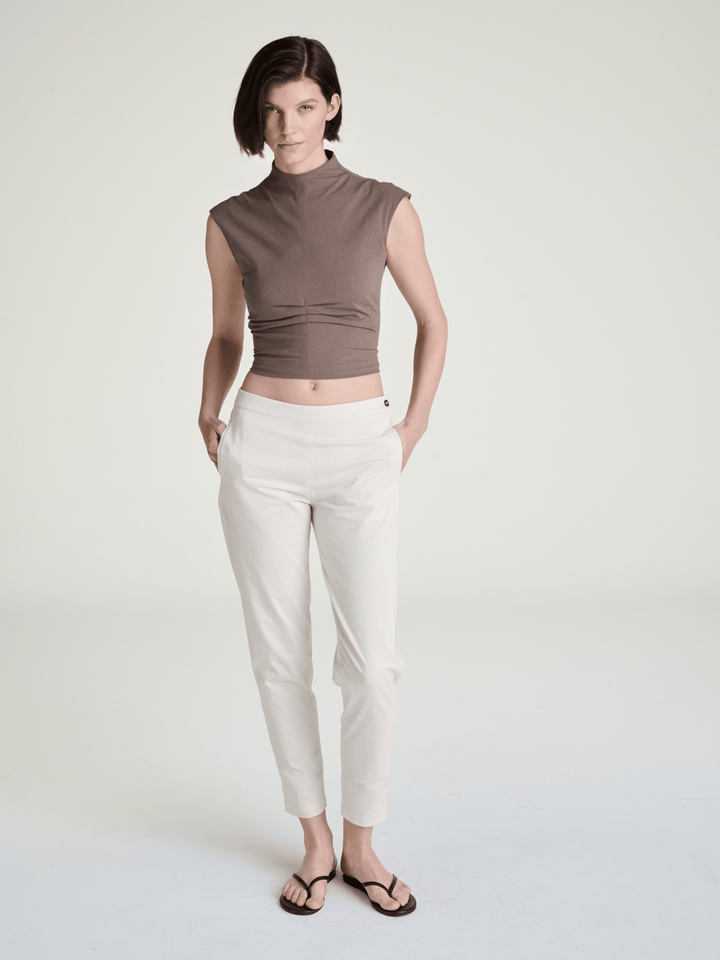 model wearing clay-beige color mockneck sleeveless jersey top and light khaki trousers
