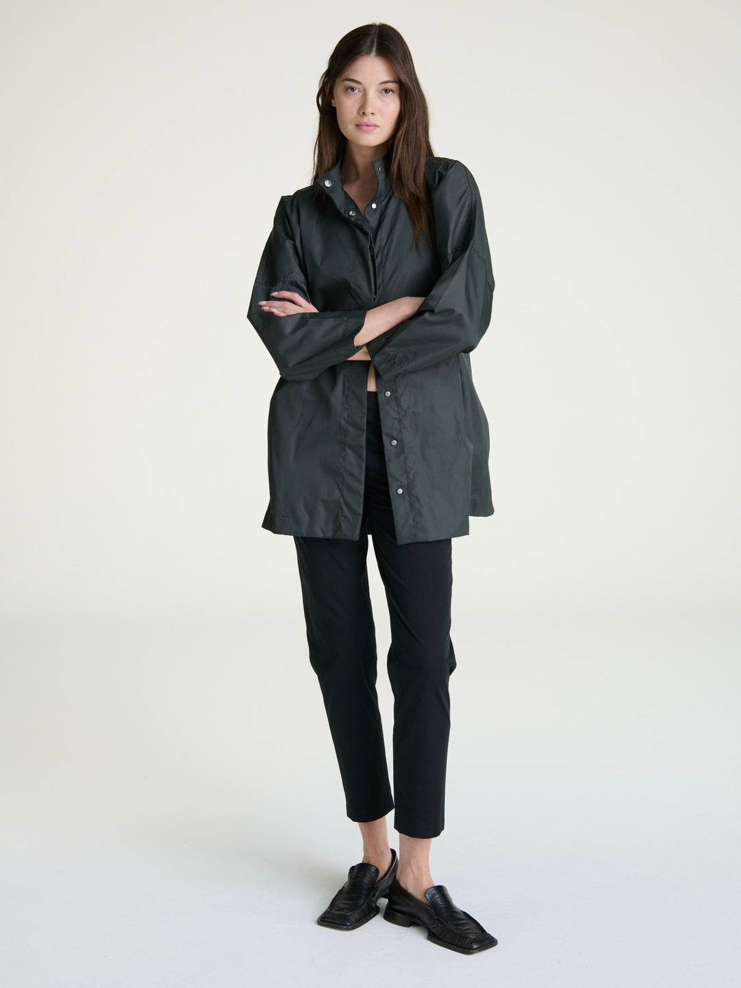 Woman wearing a dark green-grey raincoat on a gray background