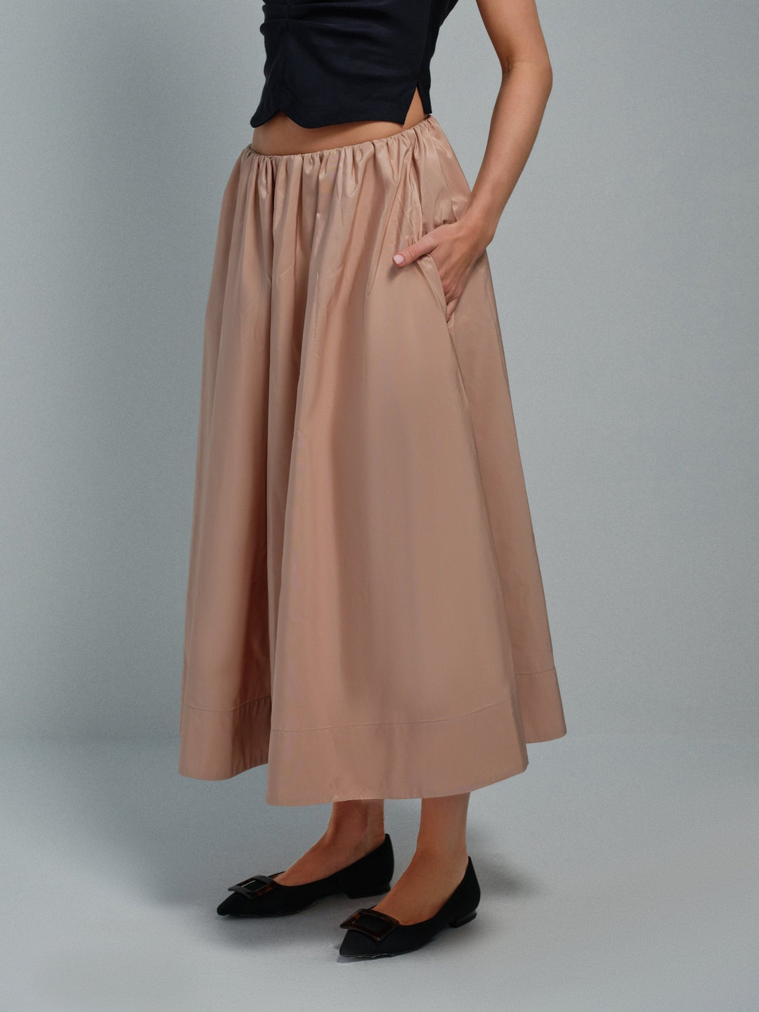 Three-quarter on-model view of blush pink taffeta midi skirt with side pockets.