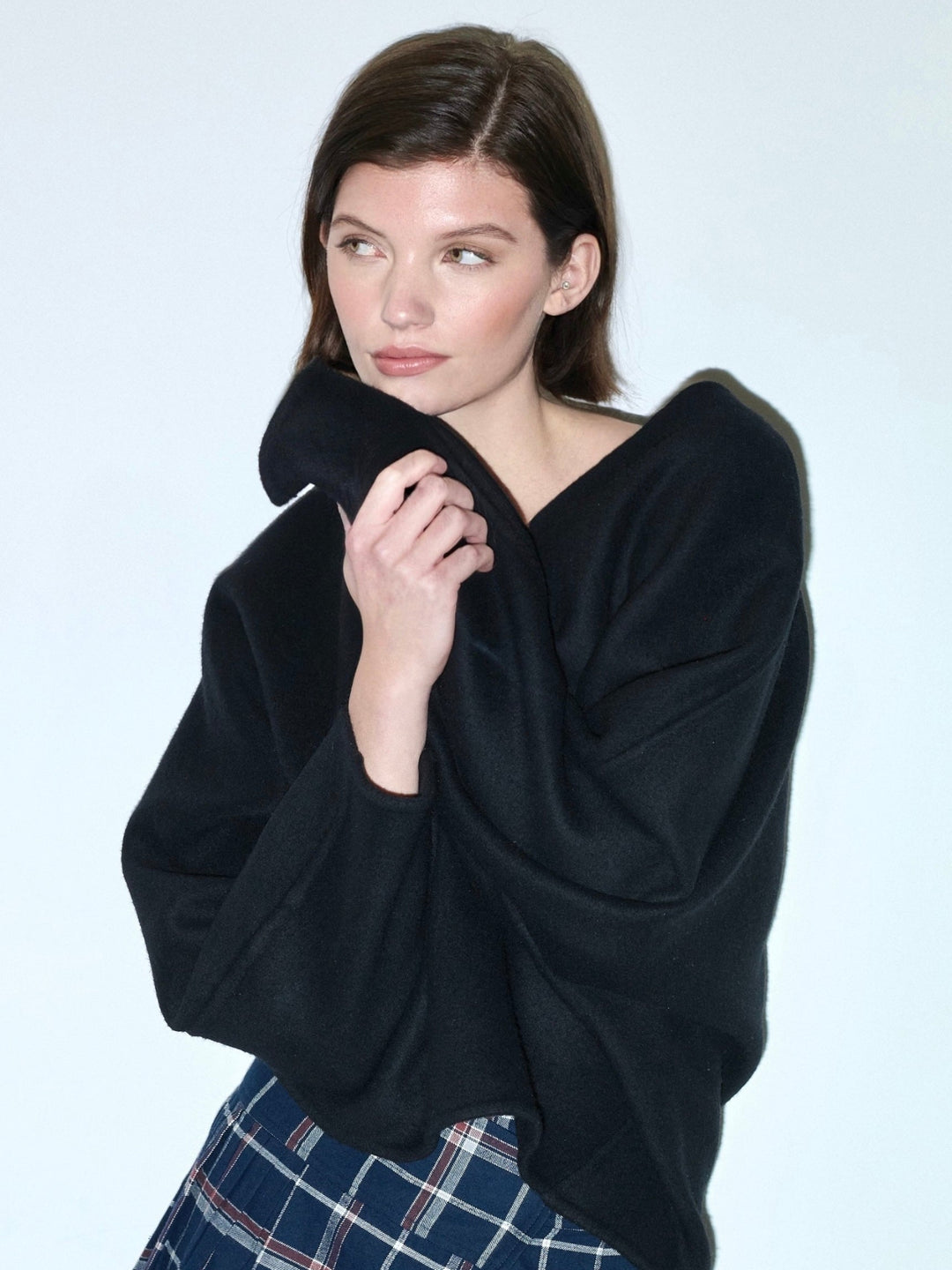 model wearing a big black sweater and plaid pleated skirt 