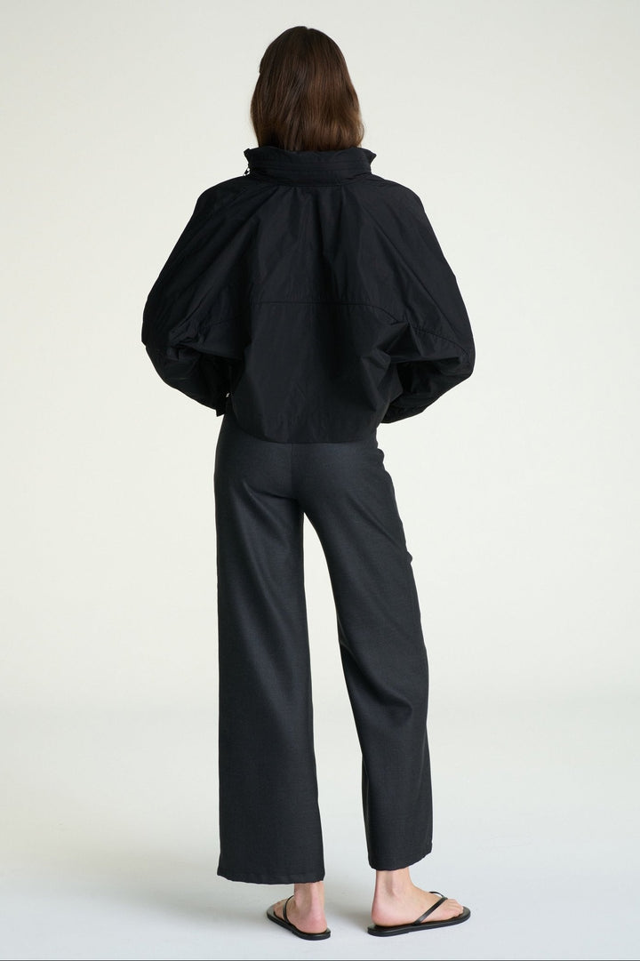 Person wearing a black jacket and pants on a white background