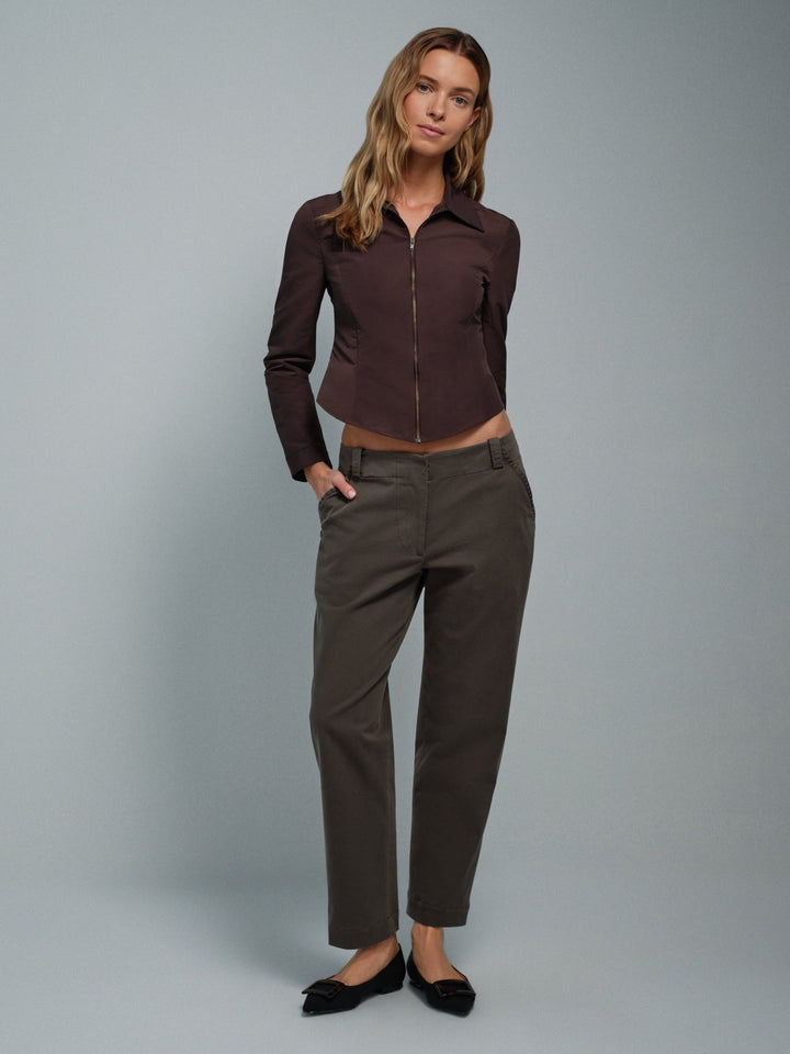 Woman wearing a brown faille collared zip-up jacket and pants on a gray background
