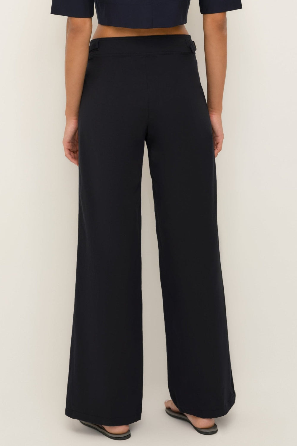Women’s black cotton wide-leg pants with ankle drawstrings, back view.