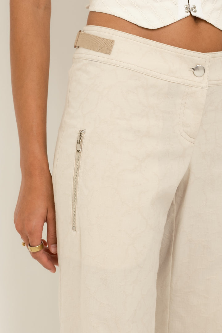 Close-up of jacquard texture with zipper pocket and waistband on women’s sand billow pants.