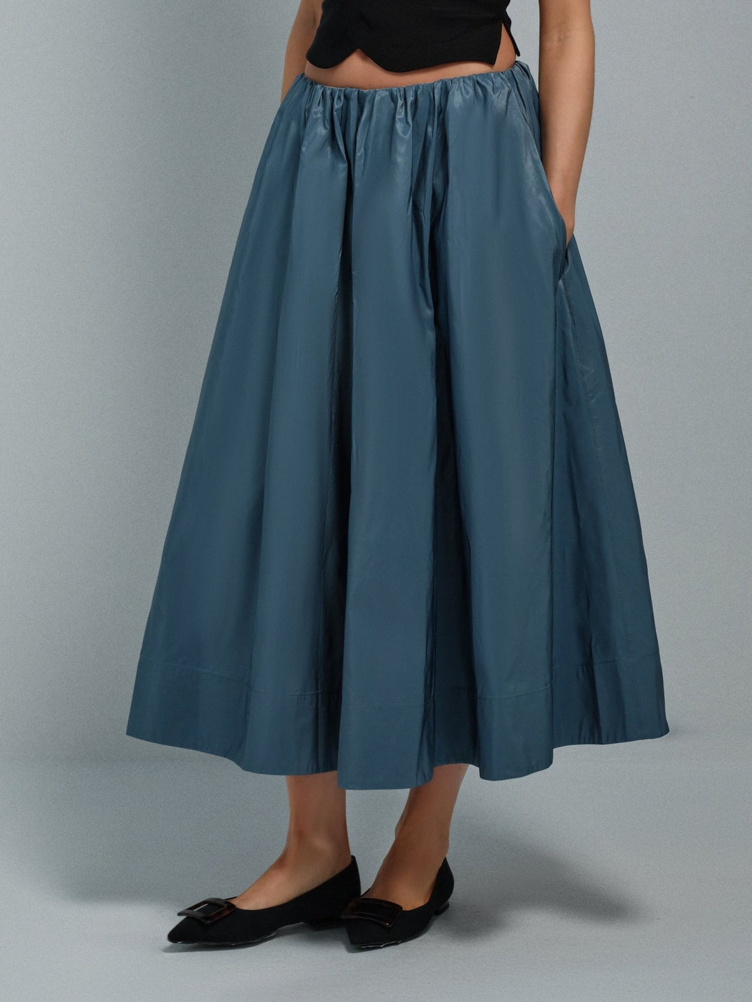 Blue full taffeta skirt worn by a person on a gray background