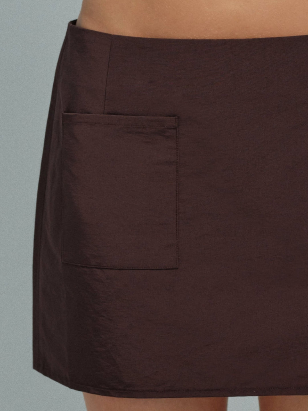 Brown mini skirt with a pocket on a neutral background