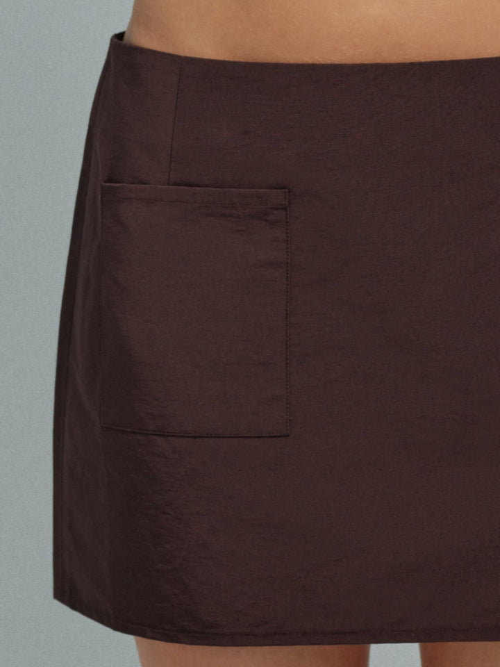Brown mini skirt with a pocket on a neutral background