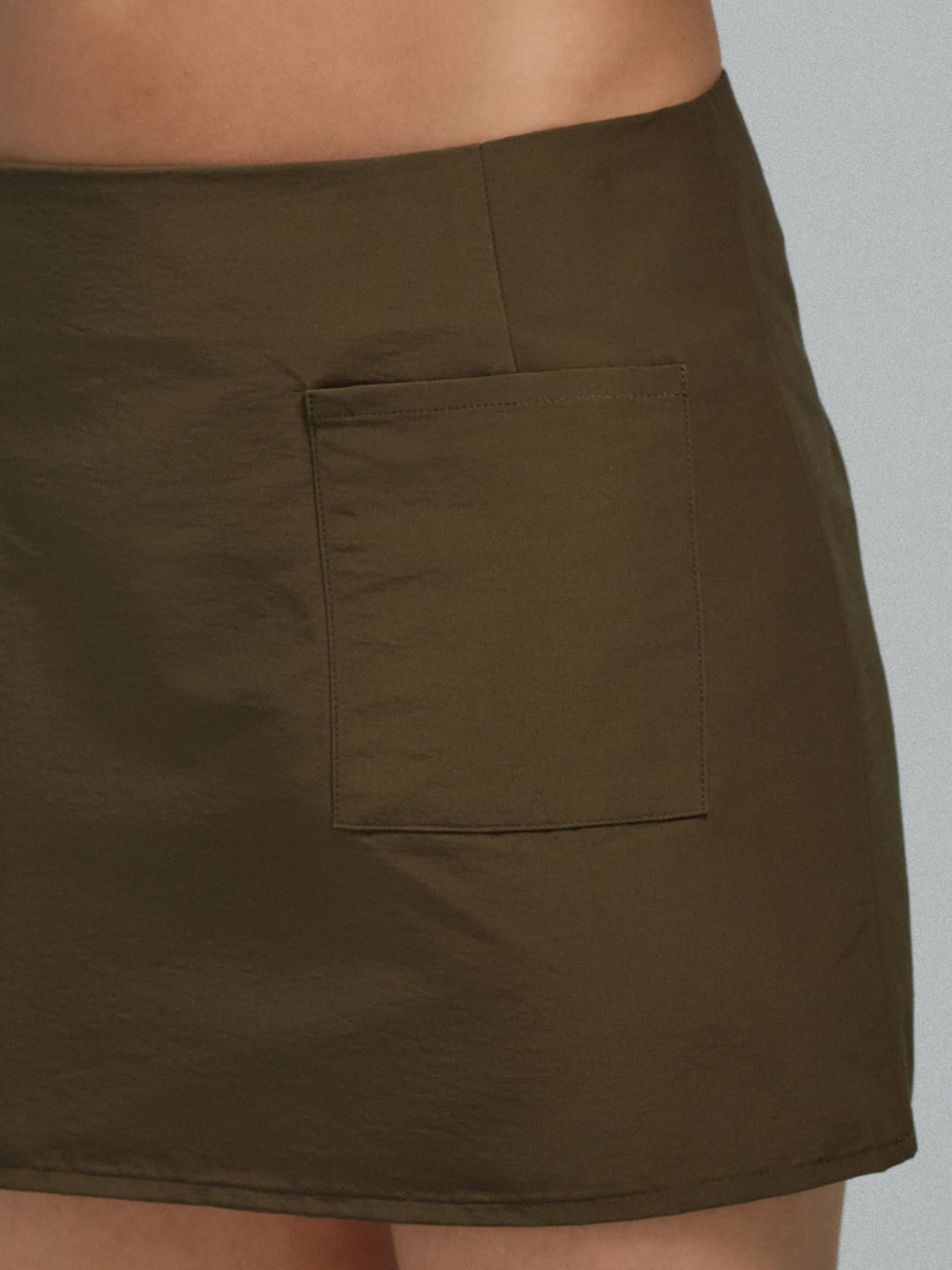 Moss green skirt with a pocket and sheeny fabric on a neutral background