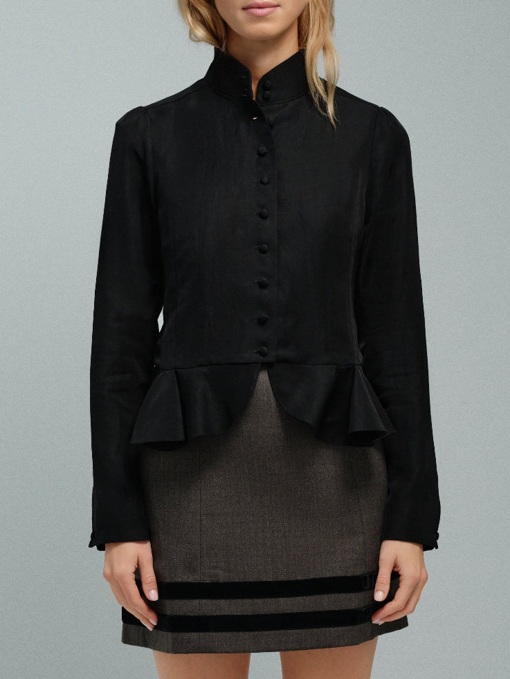 Black peplum top worn by a woman on a gray background
